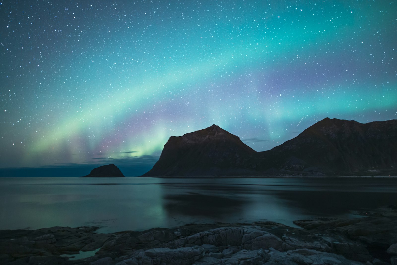 Northern lights over mountains and the sea in Lofoten